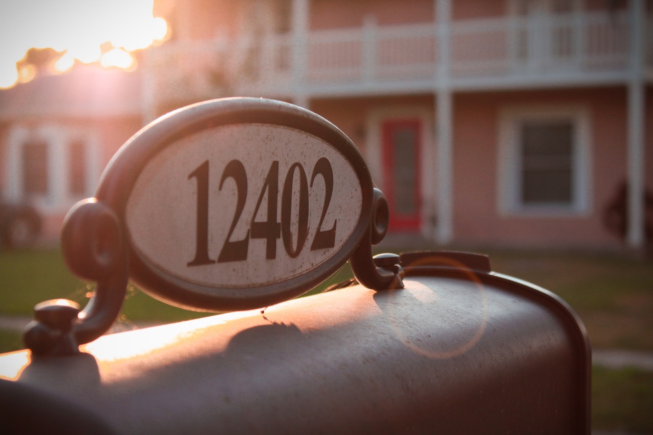A mailbox with a house address on it outside of a home, representing personal residency