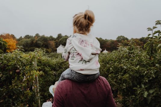 A child sitting on her parent's shoulders representing families who qualify for the Canada Child Benefit