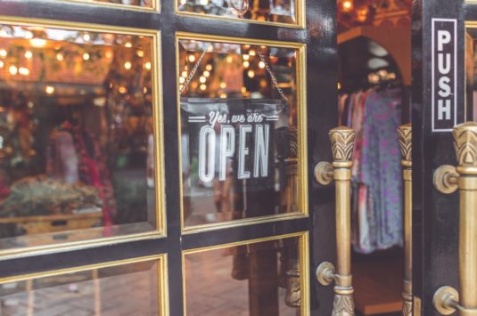 An open sign in a shop window representing small businesses seeking loans to get them through COVID-19