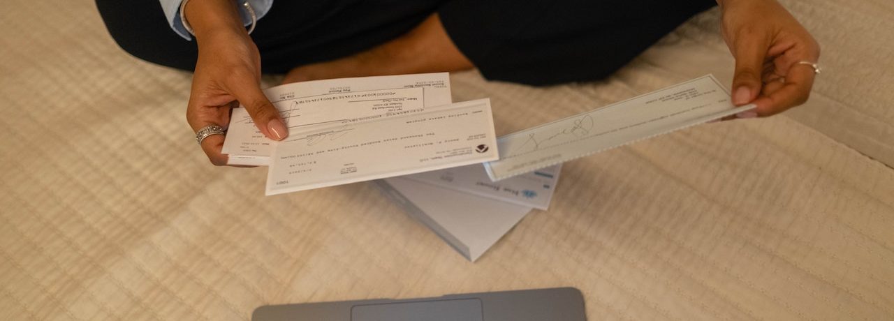 a person holding multiple cheques